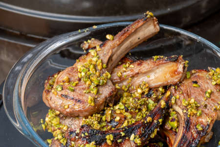 Lamb cutlets chops grilled on barbecue plate with pistachio nut . Backyard BBQ grill cooking....