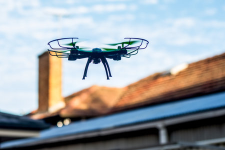 Drone quad copter flying over the roofs. Drone photography and videography. Toy drone flight. Copy spaceの写真素材