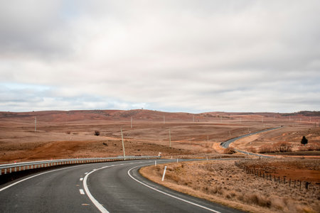 Winding open empty road surrounded by farms and fields in Outback Australia. Road trip travel...