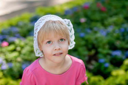 Cute blonde caucasian girl wearing white crotchet hat and pink t-shirt at the park. Summer vacation happy childhoodの写真素材