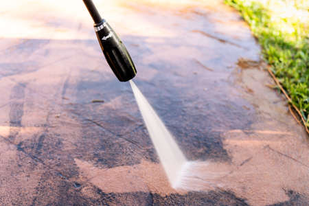Cleaning dirty backyard paving tiles with pressure washer cleaner. Spring clean upの写真素材