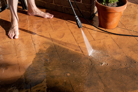 Cleaning dirty backyard paving tiles with pressure washer cleaner. Spring clean upの写真素材