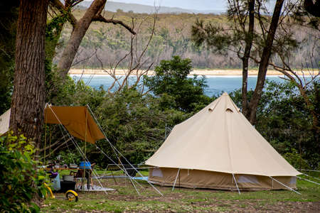 Family tent setup at the campsite surrounding by bush forest near the ocean bay in Australia. Family vacation travel camping glampingの写真素材