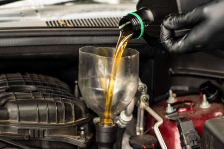 Changing replacement car oil with plastic bottle. DIY change engine motor oil. At home vehicle maintenance. Garage mechanic conceptの写真素材