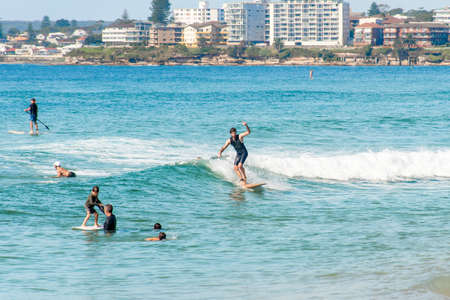 Sydney, Australia 2021-03-13 Surfers learning to catch waves in the ocean at Cronulla, NSW, Australia. Learn to surf on calm ocean.のeditorial素材