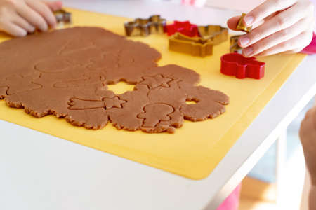 Selective focus. Kids making gingerbread cookies with various Christmas cookie cutters. Gingerbread dough. Family Christmas fun momentsの写真素材