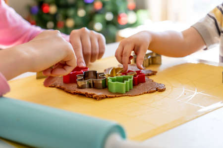 Selective focus. Kids making gingerbread cookies with various Christmas cookie cutters. Gingerbread dough. Family Christmas fun momentsの写真素材