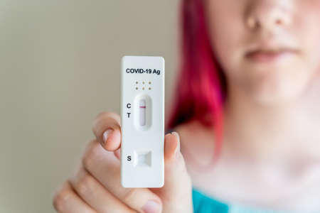 Teenage girl holding Covid-19 rapid antigen test cassette with negative result of rapid diagnostic test.の写真素材