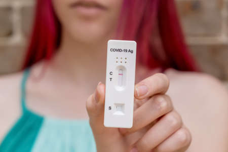 Teenage girl holding Covid-19 rapid antigen test cassette with negative result of rapid diagnostic test.の写真素材