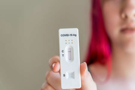 Teenage girl holding Covid-19 rapid antigen test cassette with negative result of rapid diagnostic test.の写真素材
