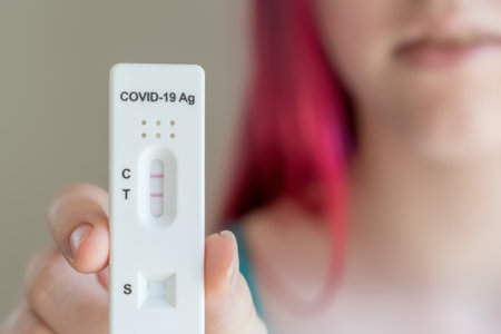 Teenage girl holding Covid-19 rapid antigen test cassette with positive result of rapid diagnostic self-testの写真素材