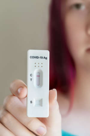 Teenage girl holding Covid-19 rapid antigen test cassette with negative result of rapid diagnostic self-testの写真素材