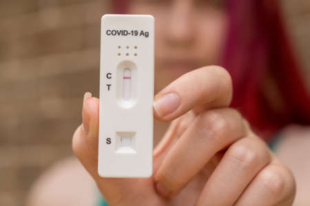 Teenage girl holding Covid-19 rapid antigen test cassette with negative result result of rapid diagnostic self-testの写真素材