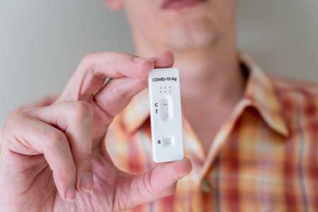 Man holding Covid-19 rapid antigen test cassette with negative result of rapid diagnostic test. Self-testing kit at homeの写真素材
