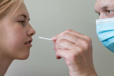 man wearing face mask and teenage girl while doing rapid antigen test nasal swab. Rapid diagnostic...