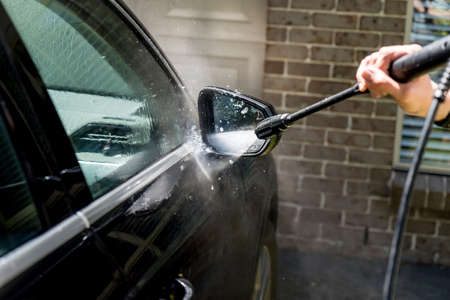 Selective focus shot of washing a black Suv 4wd car with high pressure washer cleaner. Car...