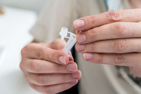 Hands holding Covid-19 rapid antigen test kit tube and cotton swab. Rapid diagnostic test...