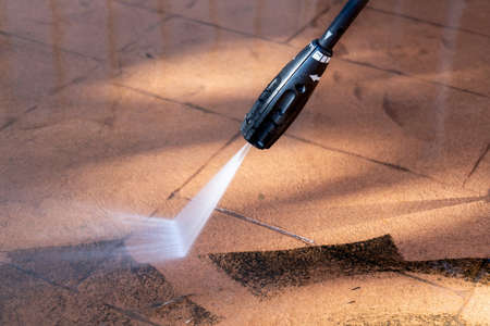 Cleaning dirty backyard paving tiles with pressure washer cleaner. Spring clean upの写真素材