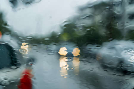 Heavy torrential rain through the windscreen. Cars with headlights on. Road safety. Flash flooding. Selective focusの写真素材