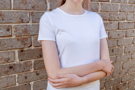 Girl wearing mockup white t-shirt on brick wall background. Template copy space fashion