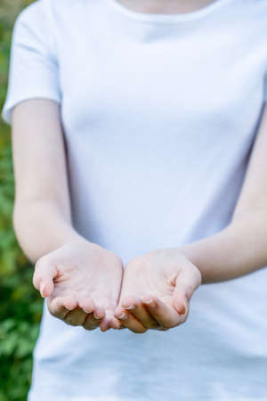 Girl wearing mockup white t-shirt with hands outstretched showing empty palms. Giving held out. copy space Templateの写真素材