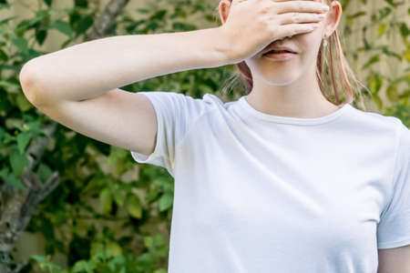 Girl wearing mockup white t-shirt covering her eyes with one hand. Template fashion design copy spaceの写真素材