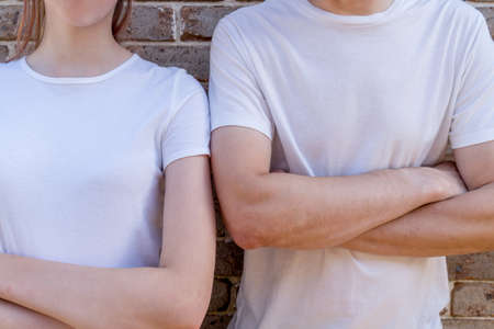 Couple wearing mockup white t-shirts on brick wall background holding hands. Template copy space fashionの写真素材