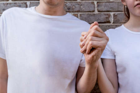 Couple wearing mockup white t-shirts on brick wall background holding hands. Template copy space fashionの写真素材