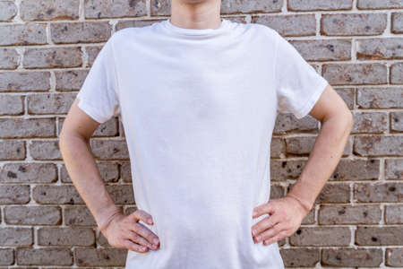 Man wearing mockup white t-shirt on brick wall background. Template copy space fashionの写真素材
