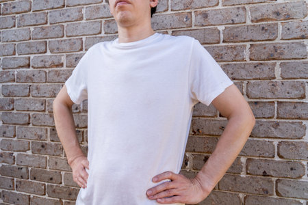 Man wearing mockup white t-shirt on brick wall background. Template copy space fashionの写真素材