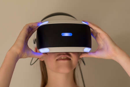 A teenage girl wearing VR headset glasses. Virtual reality simulator technology. Gamingの写真素材