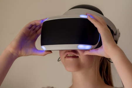 A teenage girl wearing VR headset glasses. Virtual reality simulator technology. Gamingの写真素材