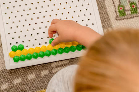 Toddler playing pegboard mosaic. Early child development. Fine motor skills. Learning and creativityの写真素材