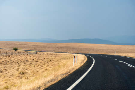 Winding open empty road surrounded by farms and fields in Australia. Road trip travel conceptの写真素材