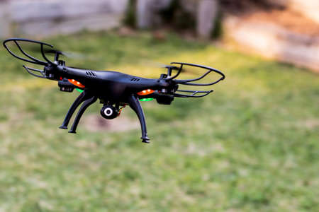 Black drone camera quad copter landing on a green grass take off. Drone photography videography aerial wireless technologyの写真素材