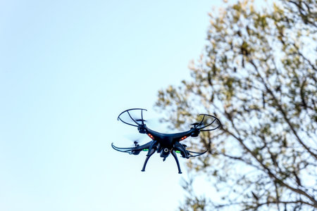 Black drone camera quad copter flying in the blue sky. Drone photography videography aerial wireless technologyの写真素材