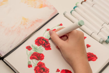 Hand drawing a red poppy wreath sketch in a sketchbook with alcohol based sketch drawing markers. Remembrance Day and Anzac day.の写真素材