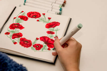 Hand drawing a red poppy wreath sketch in a sketchbook with alcohol based sketch drawing markers. Remembrance Day and Anzac day.の写真素材