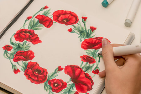 Hand drawing a red poppy wreath sketch in a sketchbook with alcohol based sketch drawing markers. Remembrance Day and Anzac day.の写真素材