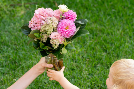Toddler holding beautiful pink bouquet with dahlia flowers. Mother's day gift present congratulations conceptの写真素材