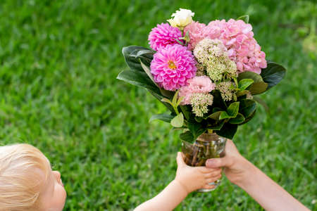 Toddler holding beautiful pink bouquet with dahlia flowers. Mother's day gift present congratulations conceptの写真素材