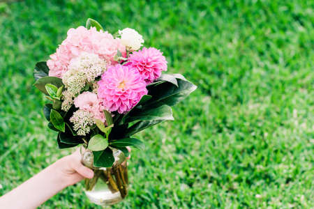 Beautiful red orange bouquet with roses. aster, peruvian lillies, dwarf everlast on green grass background. Gift present celebrationの写真素材