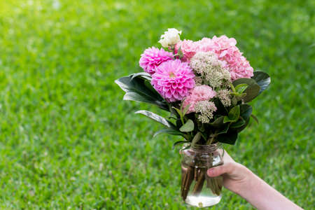 Beautiful red orange bouquet with roses. aster, peruvian lillies, dwarf everlast on green grass background. Gift present celebrationの写真素材