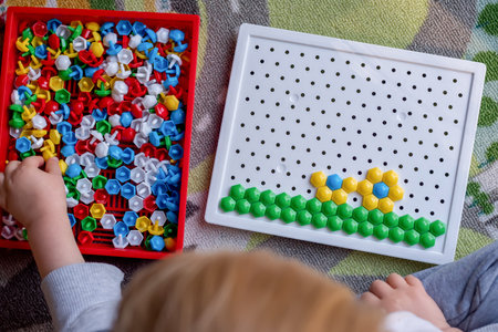 Selective focus. Toddler playing pegboard mosaic. Early child development. Fine motor skills. Learning and creativityの写真素材