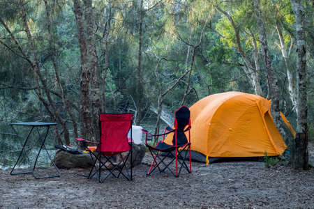Orange tent on the river bank in the forest. Travel tourism camping life conceptの写真素材