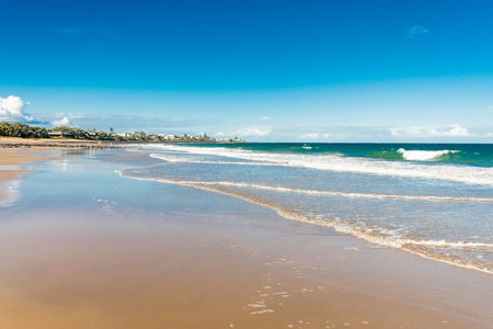 Beautiful ocean sandy beach nature background with town on the horizon. Low tidesの写真素材