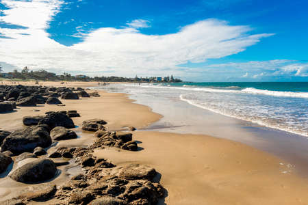 Ocean waves and sandy beach on a sunny day. Nature tropical background. Low tide with rocks exposed at Kellys Beach, Queensland, Australiaの写真素材