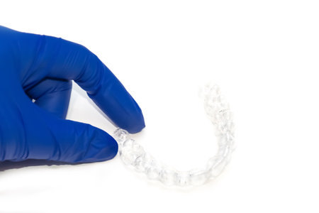Orthodontist holds clear teeth aligners. Invisible braces teeth straighteners. Clear plastic bracers ready to useの写真素材