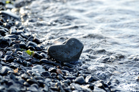 Heart shape stone against background of beach. Summer sunny day. Love, wedding and Valentine day concept. Finding beautiful and interesting stones. beach holidaysの写真素材
