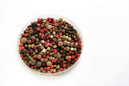 Mix of peppers in a dish - red pepper, black pepper, white pepper, green pepper isolated on white background.の写真素材